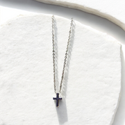 Silver dainty necklace with a small cross pendant in a white background